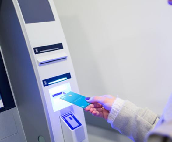 Showing a person's hand with credit card using an ATM machine